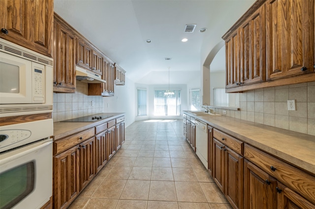 kitchen with pendant lighting, a chandelier, light tile patterned flooring, sink, and white appliances