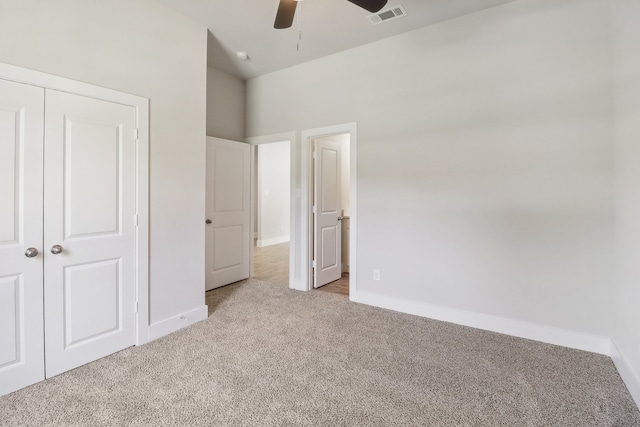 unfurnished bedroom featuring light carpet, a closet, and ceiling fan