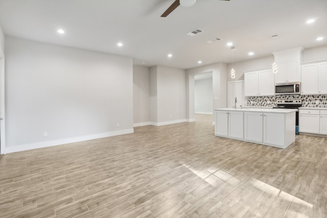 kitchen featuring ceiling fan, white cabinets, a center island with sink, appliances with stainless steel finishes, and light hardwood / wood-style floors