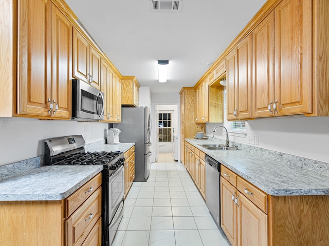 kitchen with appliances with stainless steel finishes, light tile patterned flooring, and sink