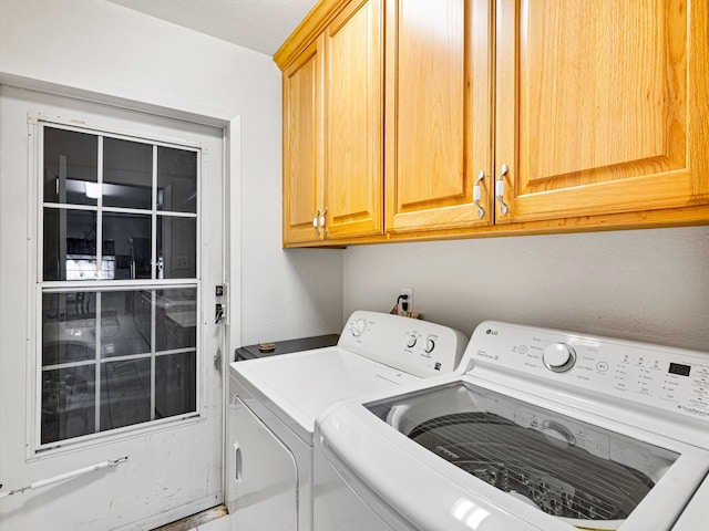 laundry area featuring a textured ceiling, washer and dryer, and cabinets