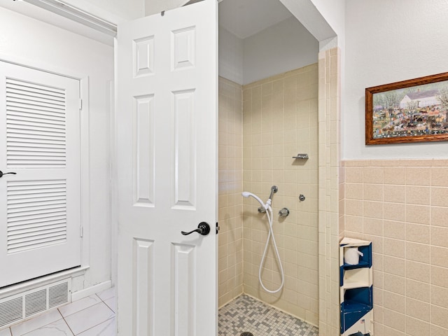 bathroom with a tile shower and tile walls