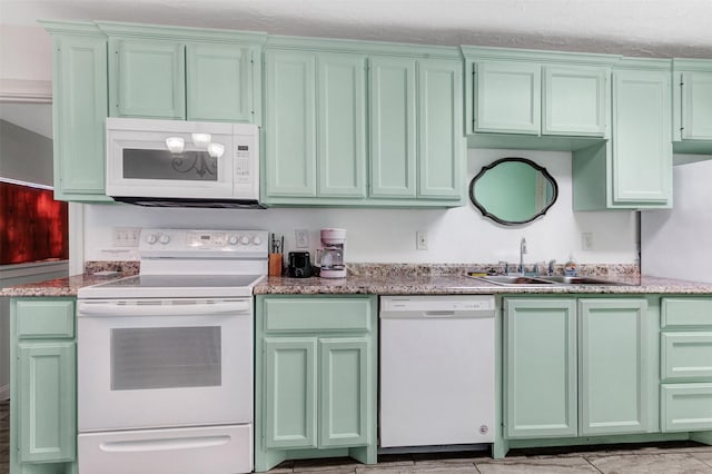 kitchen with sink, white appliances, green cabinets, and light stone counters