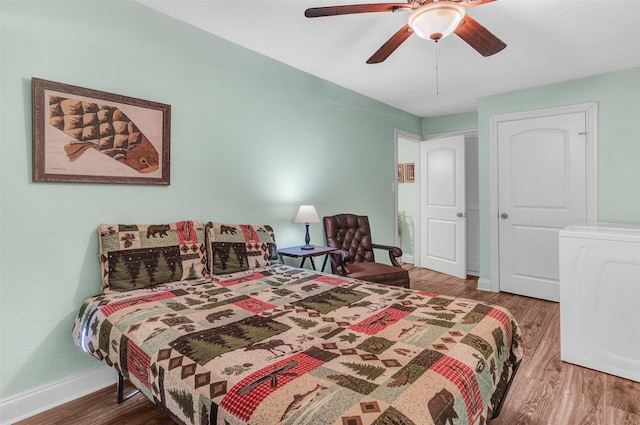 bedroom with wood-type flooring, ceiling fan, and washer / dryer