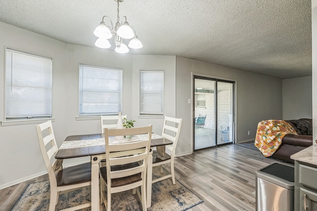 dining room with a textured ceiling, light hardwood / wood-style floors, and a notable chandelier