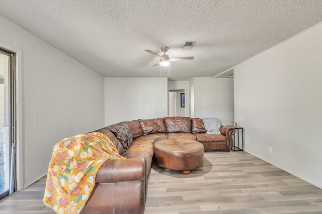 living room featuring ceiling fan, a textured ceiling, and light hardwood / wood-style floors