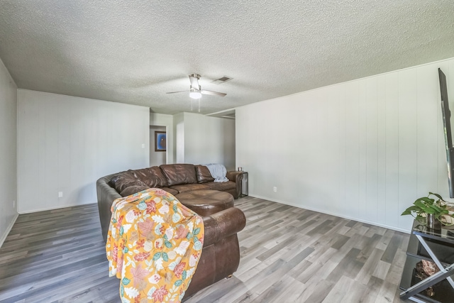 living room featuring ceiling fan, a textured ceiling, and wood-type flooring