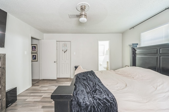 bedroom with light hardwood / wood-style floors, ensuite bathroom, ceiling fan, and a textured ceiling