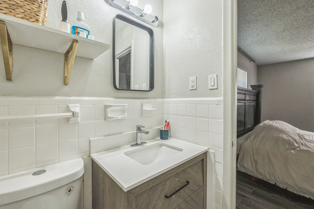 bathroom with tile walls, vanity, a textured ceiling, wood-type flooring, and toilet