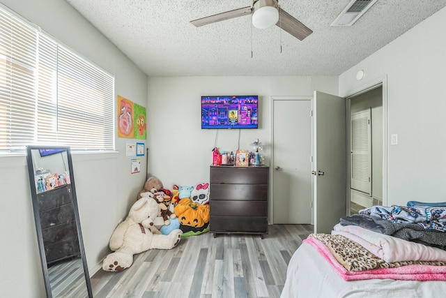 bedroom with light wood-type flooring, a textured ceiling, and ceiling fan