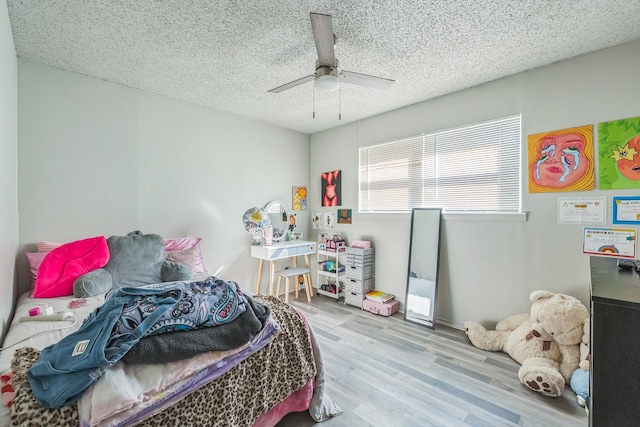 bedroom featuring ceiling fan, a textured ceiling, and light hardwood / wood-style floors