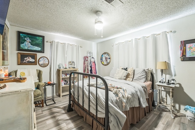 bedroom with wood-type flooring, ceiling fan, and a textured ceiling