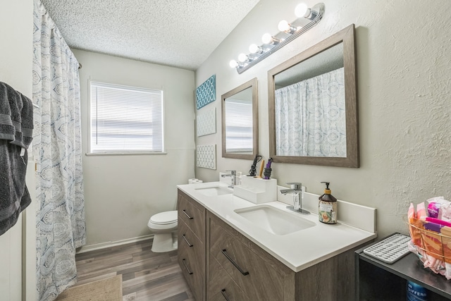 bathroom with a textured ceiling, hardwood / wood-style flooring, vanity, and toilet