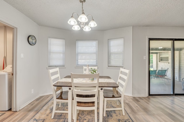 dining space featuring washer / clothes dryer, an inviting chandelier, light wood-type flooring, and a textured ceiling