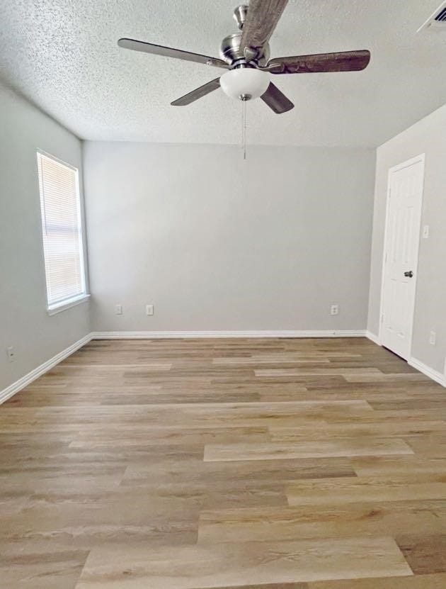 empty room featuring light hardwood / wood-style flooring, ceiling fan, and a textured ceiling