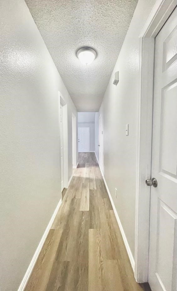 hallway with a textured ceiling and hardwood / wood-style floors