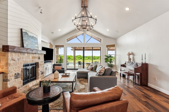 living room with an inviting chandelier, a stone fireplace, hardwood / wood-style flooring, and lofted ceiling