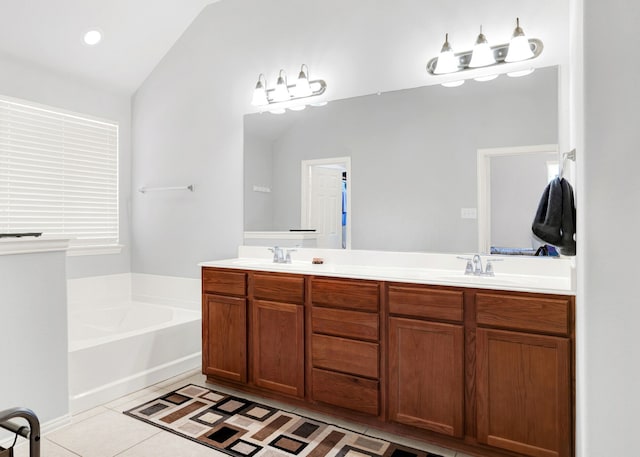 bathroom with tile patterned flooring, vaulted ceiling, vanity, and a bathing tub