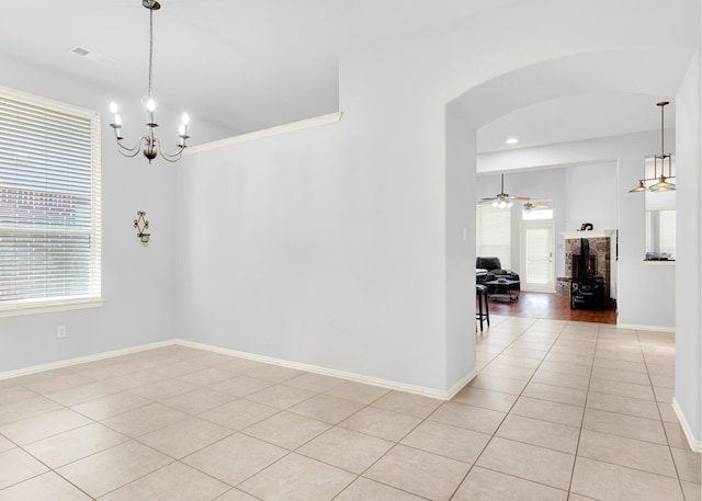 unfurnished room featuring a healthy amount of sunlight, ceiling fan with notable chandelier, and light tile patterned flooring