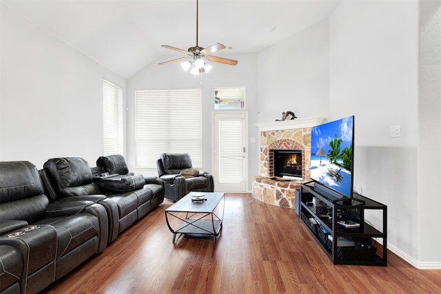 living room featuring ceiling fan, a stone fireplace, lofted ceiling, and wood-type flooring