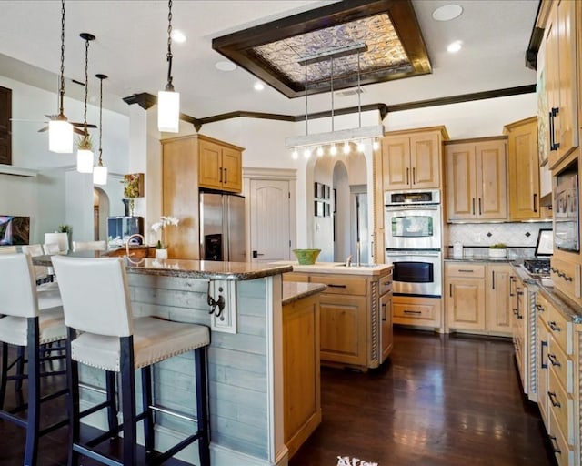 kitchen featuring dark hardwood / wood-style floors, a center island, stainless steel appliances, and decorative light fixtures