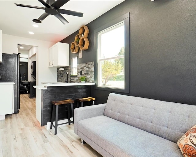 living room featuring ceiling fan, light hardwood / wood-style flooring, and sink