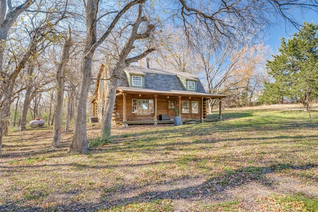 view of front of house with a front lawn, log siding, covered porch, and a shingled roof