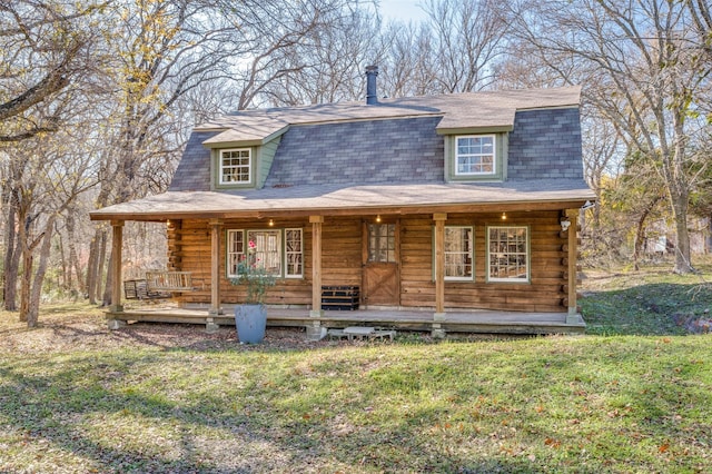 log-style house featuring log siding, covered porch, a shingled roof, and a front lawn