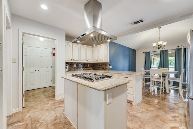 kitchen with pendant lighting, tasteful backsplash, a kitchen island, island exhaust hood, and a notable chandelier