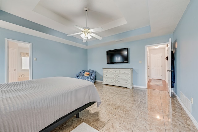 bedroom featuring ceiling fan, a tray ceiling, and ensuite bathroom