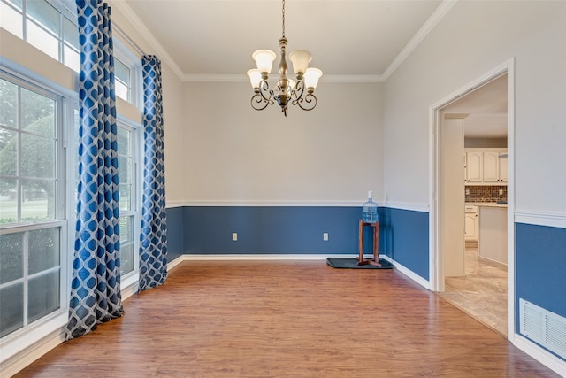 unfurnished room with a chandelier, light hardwood / wood-style floors, and crown molding