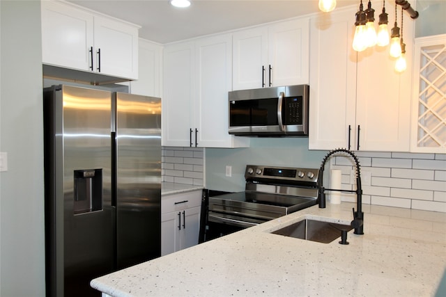 kitchen with stainless steel appliances, light stone countertops, and white cabinets