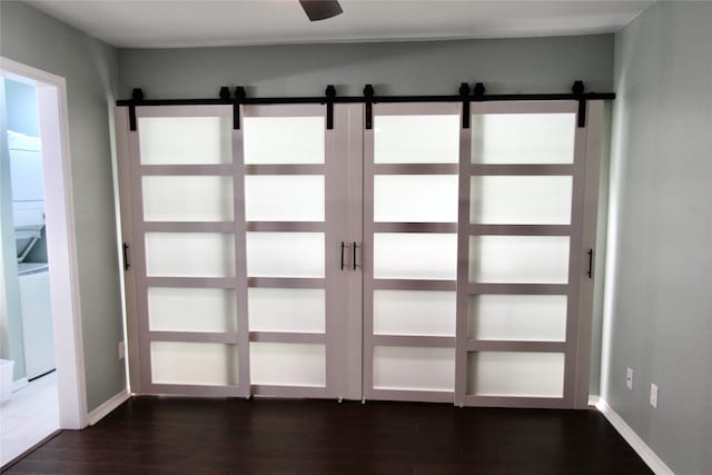 doorway to outside with a barn door, ceiling fan, and dark wood-type flooring