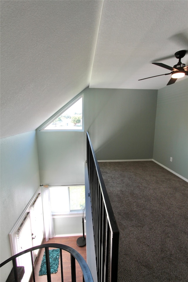 stairs featuring carpet floors, vaulted ceiling, a wealth of natural light, and a textured ceiling