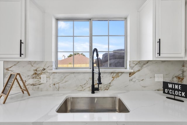 kitchen with light stone counters, sink, decorative backsplash, and white cabinets