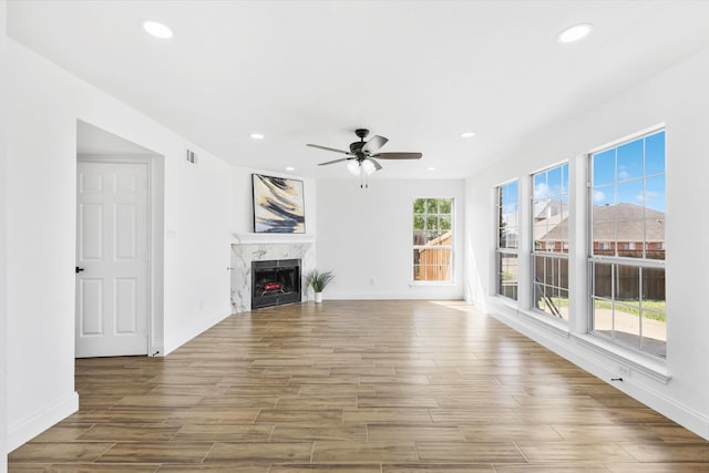 unfurnished living room featuring ceiling fan and a fireplace