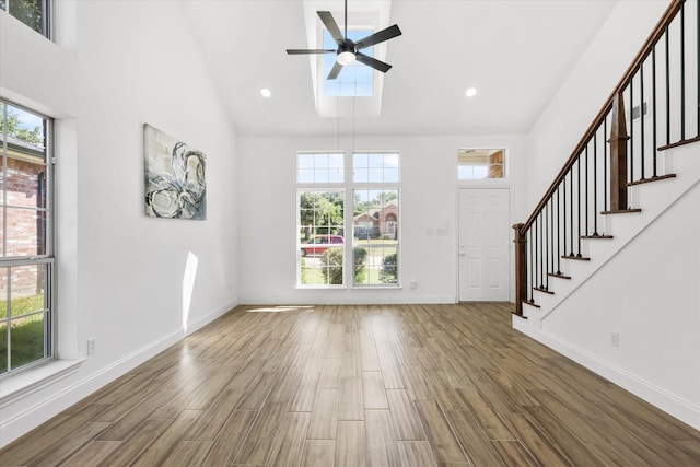 foyer entrance featuring hardwood / wood-style flooring, a towering ceiling, and ceiling fan