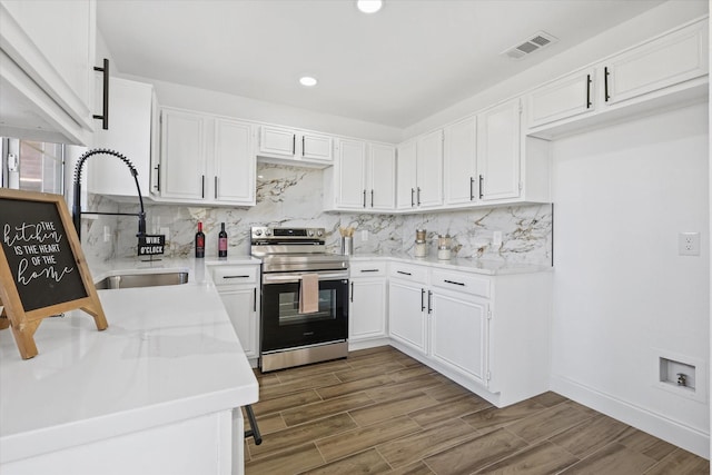 kitchen with light stone counters, sink, stainless steel range with electric cooktop, and white cabinets