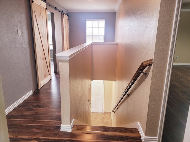 stairway featuring a barn door, crown molding, and wood-type flooring