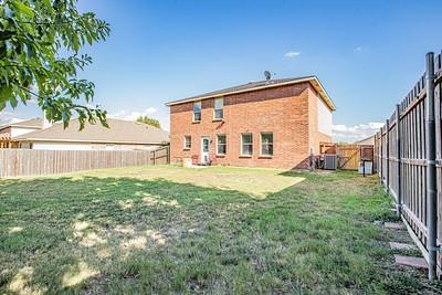 rear view of house featuring central AC and a lawn