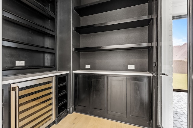 bar with light hardwood / wood-style flooring and wine cooler