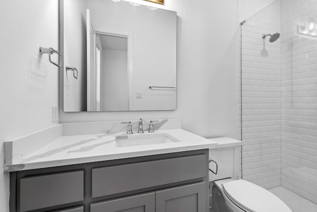 bathroom featuring a tile shower, vanity, and toilet