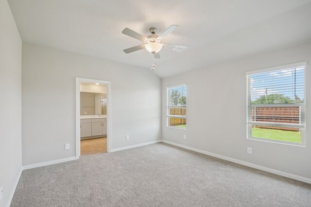 spare room featuring light carpet, plenty of natural light, vaulted ceiling, and ceiling fan