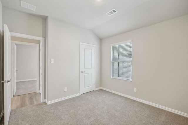 empty room featuring light colored carpet and vaulted ceiling