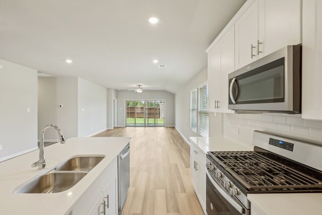 kitchen with white cabinets, sink, a center island with sink, appliances with stainless steel finishes, and light hardwood / wood-style floors