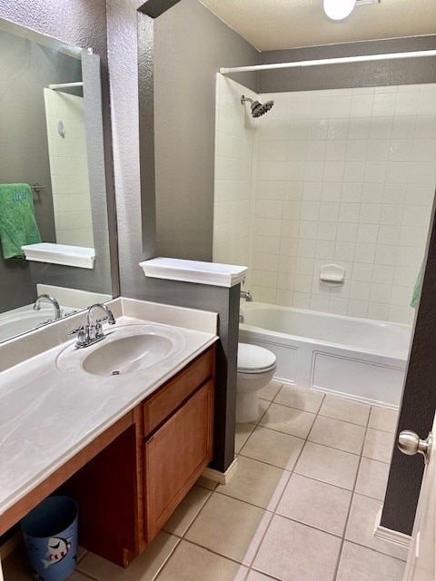 full bathroom with tile patterned flooring, tiled shower / bath combo, vanity, and toilet