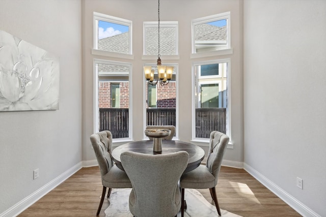 dining area featuring a wealth of natural light, a chandelier, wood-type flooring, and a high ceiling