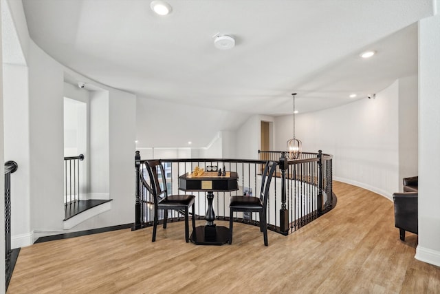 corridor with an inviting chandelier, vaulted ceiling, and light hardwood / wood-style floors