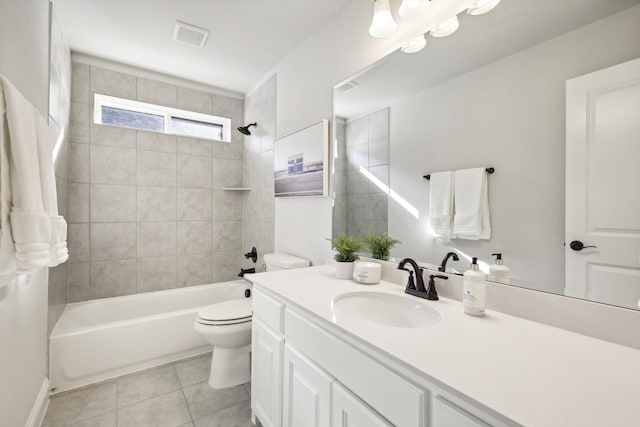 full bathroom with tile patterned flooring, tiled shower / bath, vanity, and toilet