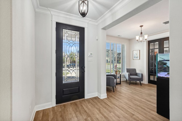 entryway featuring a chandelier, light hardwood / wood-style floors, and crown molding